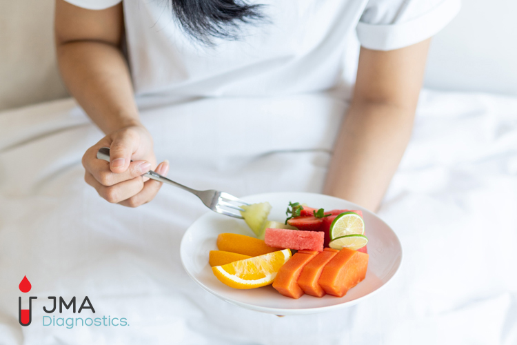 woman in a white shirt eating fruits after a blood test